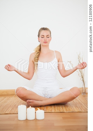 Peaceful blonde sitting in lotus pose on bamboo mat 12180906