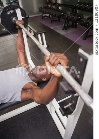 Determined muscular man lifting barbell in gym 12180907