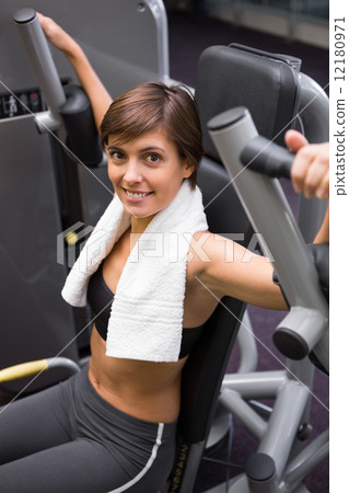 Happy brunette using weights machine for arms Happy brunette using weights machine for arms 12180971