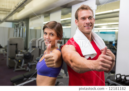 Fit attractive couple smiling at camera showing thumbs up 12181182