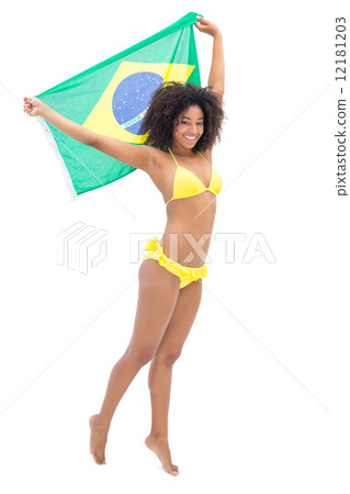 Fit girl in yellow bikini holding brazil flag smiling at camera 12181203