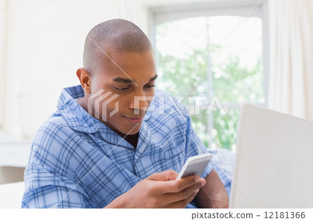 Happy man using laptop on bed and texting Happy man using laptop on bed and texting 12181366