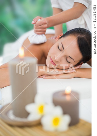 Beautiful brunette enjoying a herbal compress massage 12181482