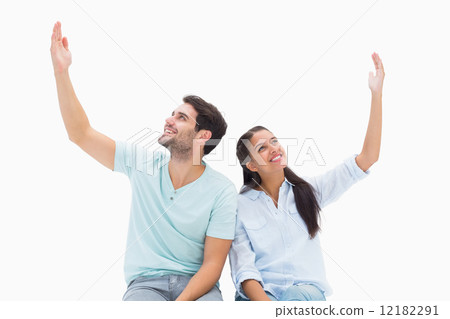 Cute couple sitting with arms raised 12182291