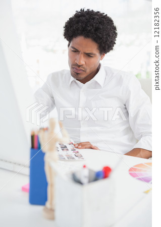 Hipster photo editor working at his desk Hipster photo editor working at his desk 12182356