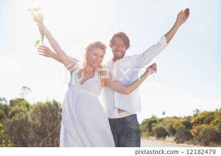 Attractive couple standing with arms raised by the road Attractive couple standing with arms raised by the road 12182479