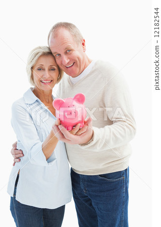 Happy mature couple smiling at camera showing piggy bank 12182544