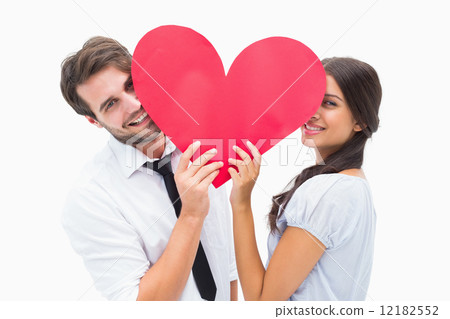 Couple smiling at camera holding a heart Couple smiling at camera holding a heart 12182552