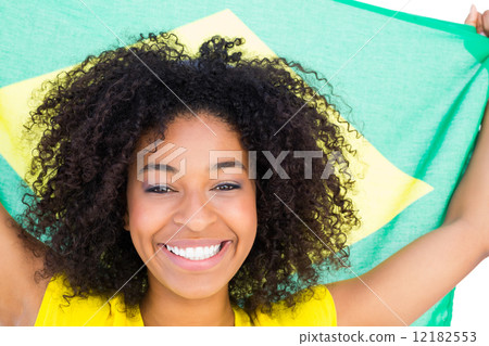 Pretty girl in yellow tshirt holding brazilian flag smiling at c 12182553