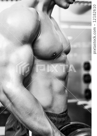 Mid section of shirtless muscular man exercising with dumbbell 12182610
