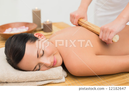 Beautiful brunette enjoying a bamboo roller massage Beautiful brunette enjoying a bamboo roller massage 12182647