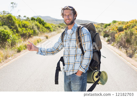 Attractive man hitch hiking on rural road 12182703