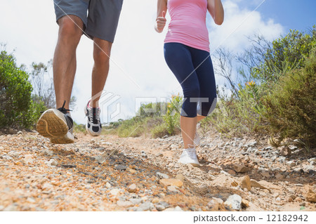 Fit couple running down mountain trail 12182942
