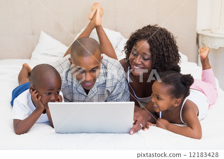 Happy family using laptop together on bed Happy family using laptop together on bed 12183428