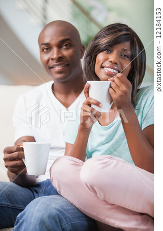 Happy couple sitting on couch having coffee Happy couple sitting on couch having coffee 12184153
