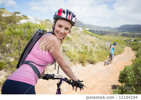 Fit couple cycling on mountain trail woman smiling at camera Fit couple cycling on mountain trail woman smiling at camera 12184284