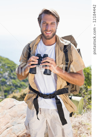 Handsome hiker holding binoculars on mountain trail 12184442