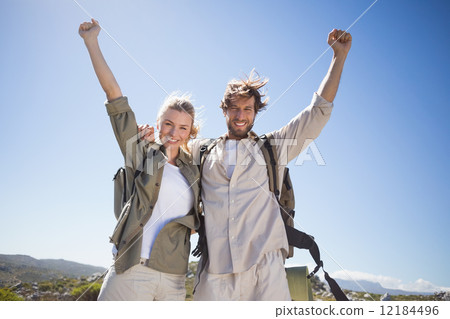 Hiking couple standing on mountain terrain smiling at camera 12184496