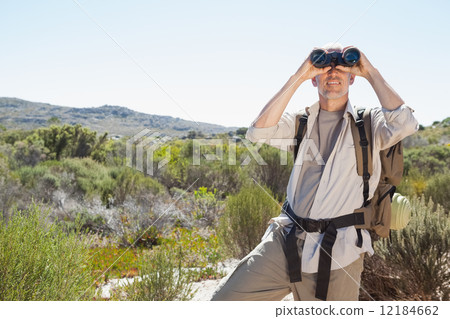 Hiker looking through binoculars on country trail 12184662