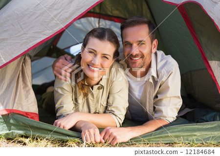 Outdoorsy couple smiling at camera from inside their tent Outdoorsy couple smiling at camera from inside their tent 12184684