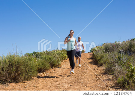 Fit couple running down mountain trail 12184764