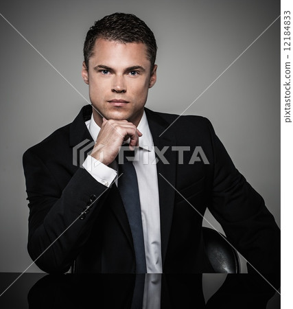 Handsome young well-dressed man in jacket behind table Handsome young well-dressed man in jacket behind table 12184833