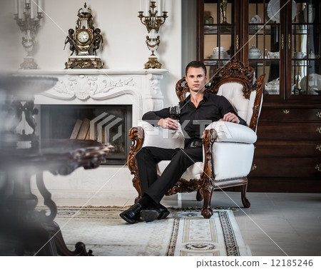 Handsome well-dressed man sitting with red wine in luxury house interior Handsome well-dressed man sitting with red wine in luxury house interior 12185246