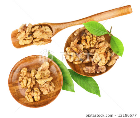Handful of walnuts in wooden bowls, scoop and green leaves. 12186677