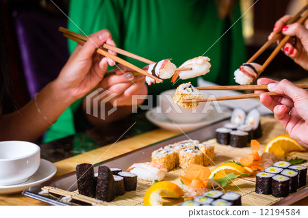Young people eating sushi in Asian restaurant 12194584