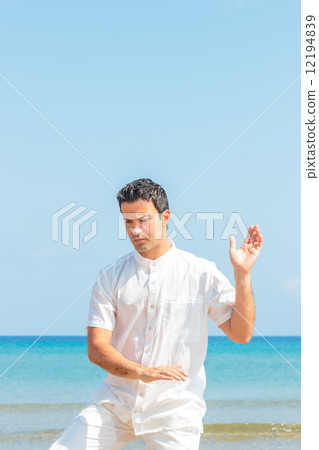 Handsome man on the beach meditating Handsome man on the beach meditating 12194839
