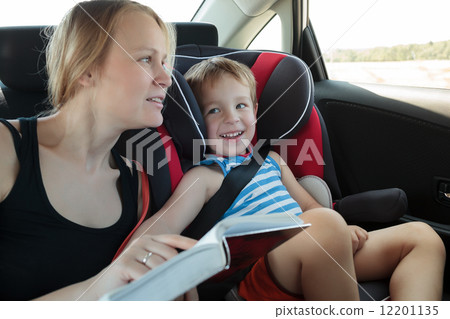 Mother reading a book to son in the car 12201135