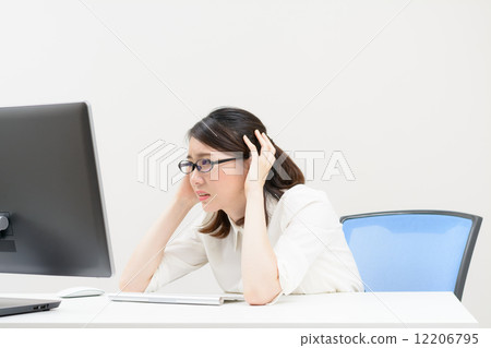 A woman holding her head by looking at the computer screen A woman holding her head by looking at the computer screen 12206795