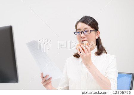 A woman working while eating a donut A woman working while eating a donut 12206796