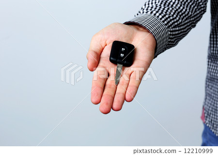 Hand holding car keys isolated on gray background 12210999
