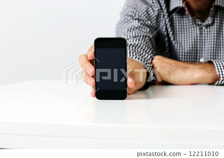 Closeup image of a man sitting at the table and showing smartphone screen Closeup image of a man sitting at the table and showing smartphone screen 12211010