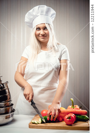 Woman wearing uniform cutting vegetables for a salad Woman wearing uniform cutting vegetables for a salad 12211944