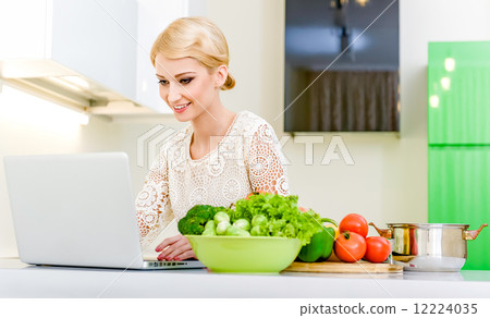 Young woman looking for a recipe on the laptop computer Young woman looking for a recipe on the laptop computer 12224035