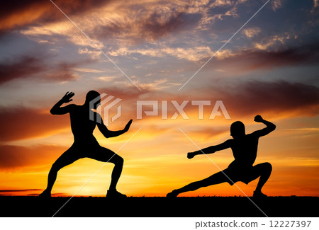 Silhouettes of two fighters on sunset fiery background 12227397