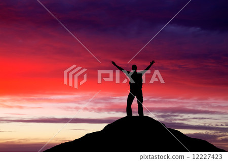 Silhouette of a man on a mountain top. Person silhouette on the 12227423