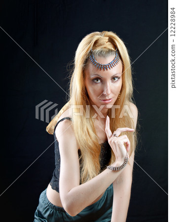 beautiful young blonde woman with long hair and jewellery, warning sign points a finger on dark back 12228984