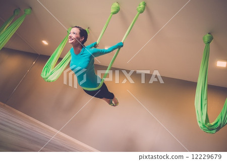 Young woman performing antigravity yoga exercise 12229679