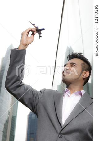 Portrait of Asian business executive holding toy plane 12243295