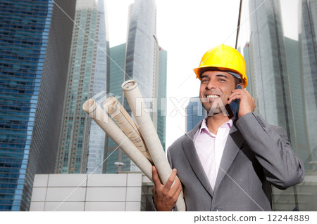 Asian business executive with hard hat and architectural plans on phone Asian business executive with hard hat and architectural plans on phone 12244889