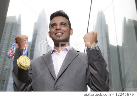 Asian businessman holding medals looking ahead 12245679
