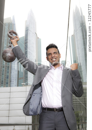 Asian Businessman holding ball and shackles outdoors 12245777