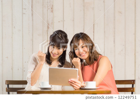 Two women who gaze pose when looking at the tablet PC Two women who gaze pose when looking at the tablet PC 12249751