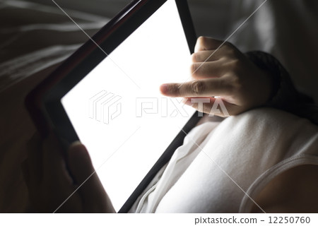 Woman using tablet at night in bed Woman using tablet at night in bed 12250760