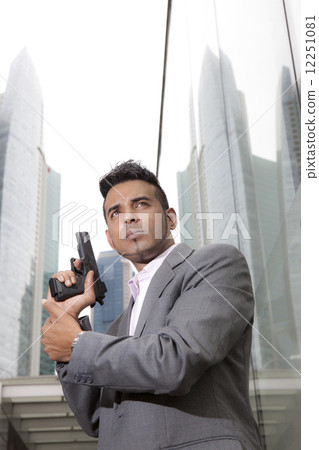 Businessman holding gun outdoors 12251081
