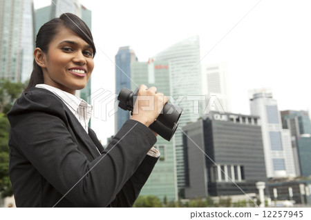 Businesswoman holding binoculars outdoors 12257945