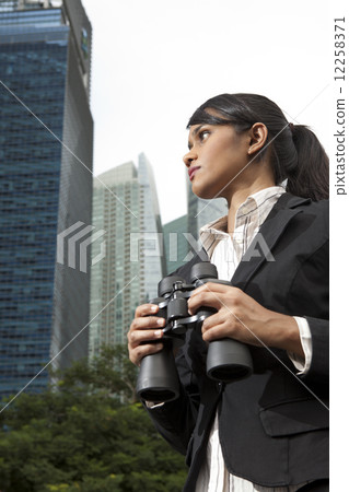 Businesswoman holding binoculars outdoors 12258371